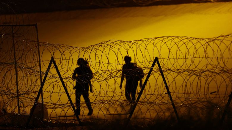 Haitian migrants walk past a razor wire fence deployed to inhibit the crossing of migrants into the United States, as seen from Ciudad Juarez, Mexico July 28, 2023. 