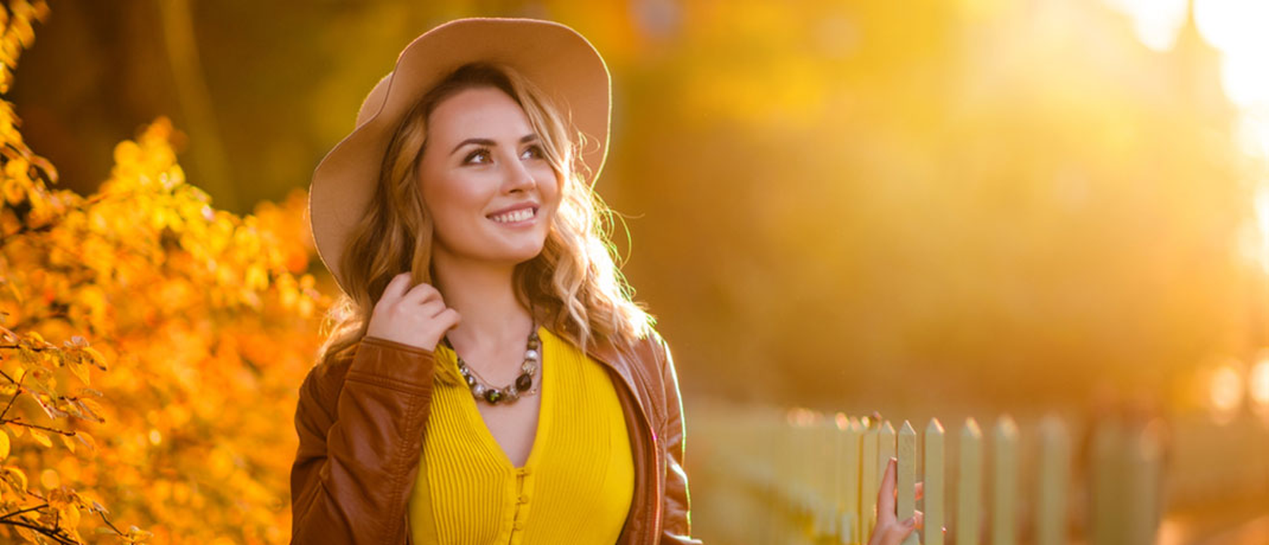 Young smiling woman wearing a hat outside at dusk