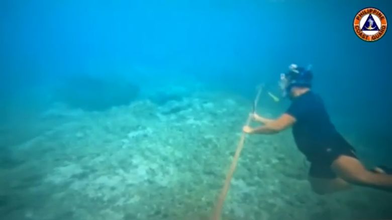 A diver cuts off a Chinese floating barrier in a disputed area of the South China Sea.