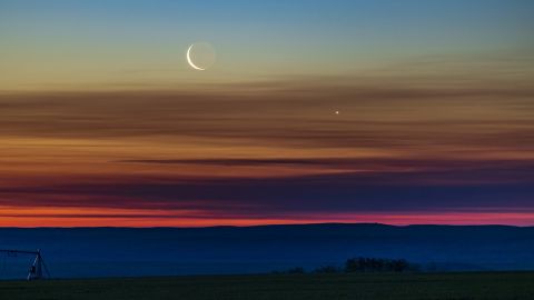 The conjunction of the waning crescent Moon with Venus as they were rising low in the northeast dawn sky on June 26, 2022, taken from home in southern Alberta, latitude 51° N. Earthshine is visible on the dark side of the Moon. The sky exhibits the wonderful transition of colours from the orange at the horizon through the spectrum to the blues at top. This is a single 1-second exposure with the RF70-200mm lens at 200mm and f/4 on the Canon R5 at ISO 400. (Photo by: Alan Dyer/VW Pics/Universal Images Group via Getty Images)