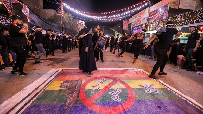 Shiite Muslim devotees self-flagellate over an unfurled banner on the ground depicting the Pride rainbow flag defaced with a boot and the Arabic slogan "no to homosexual society," in Iraq's southern city of Nasiriyah on July 25.