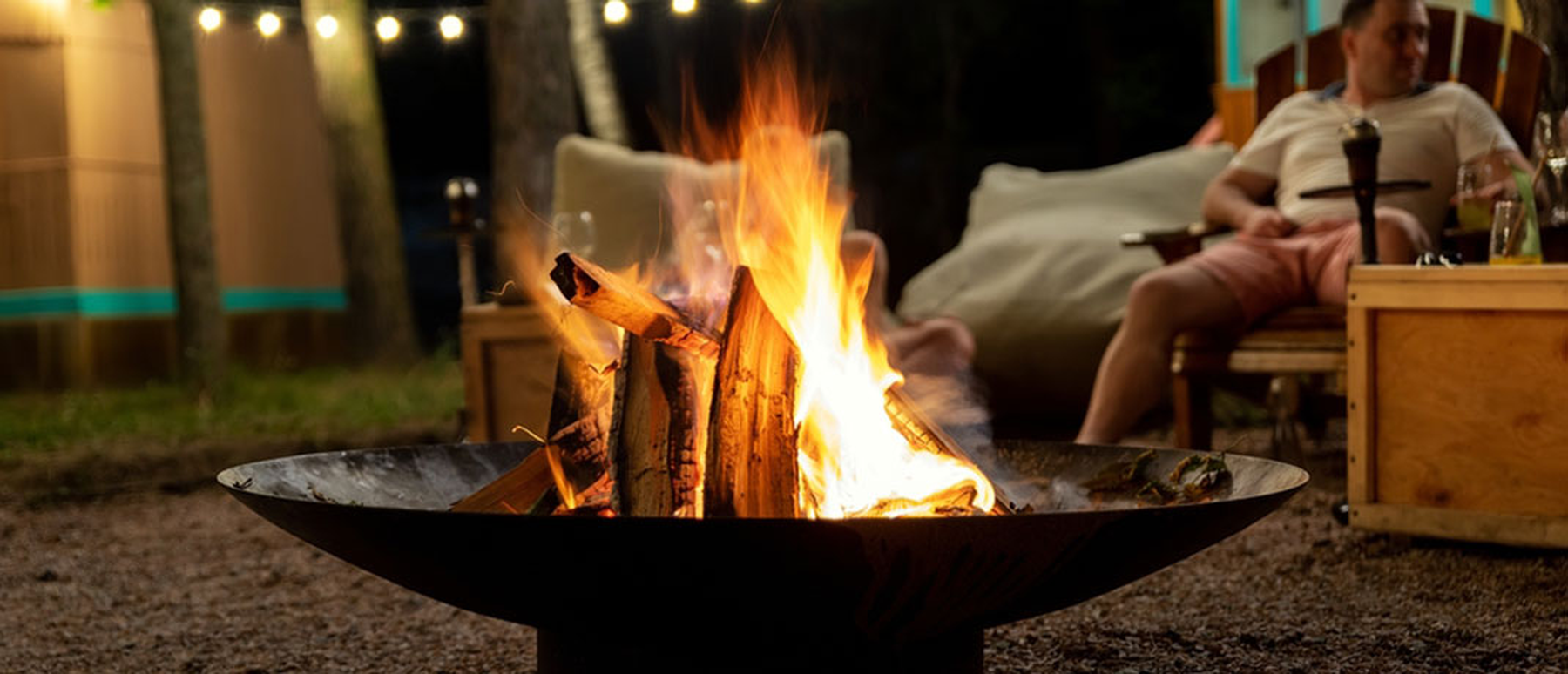 Man sitting by a firepit on his patio at night