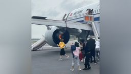 The image shows passengers evacuate an Air China plane with its engine on fire. 