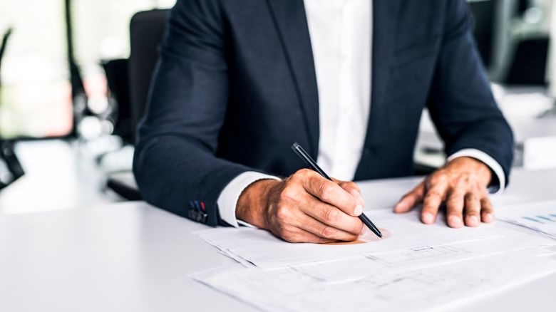 Close-up of businessman with documents at desk in office - stock photo