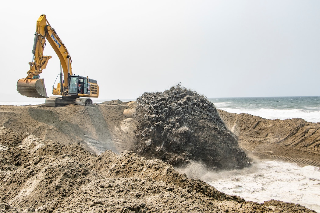 Beach front, ocean, sand being pumped ashore, construction equipment