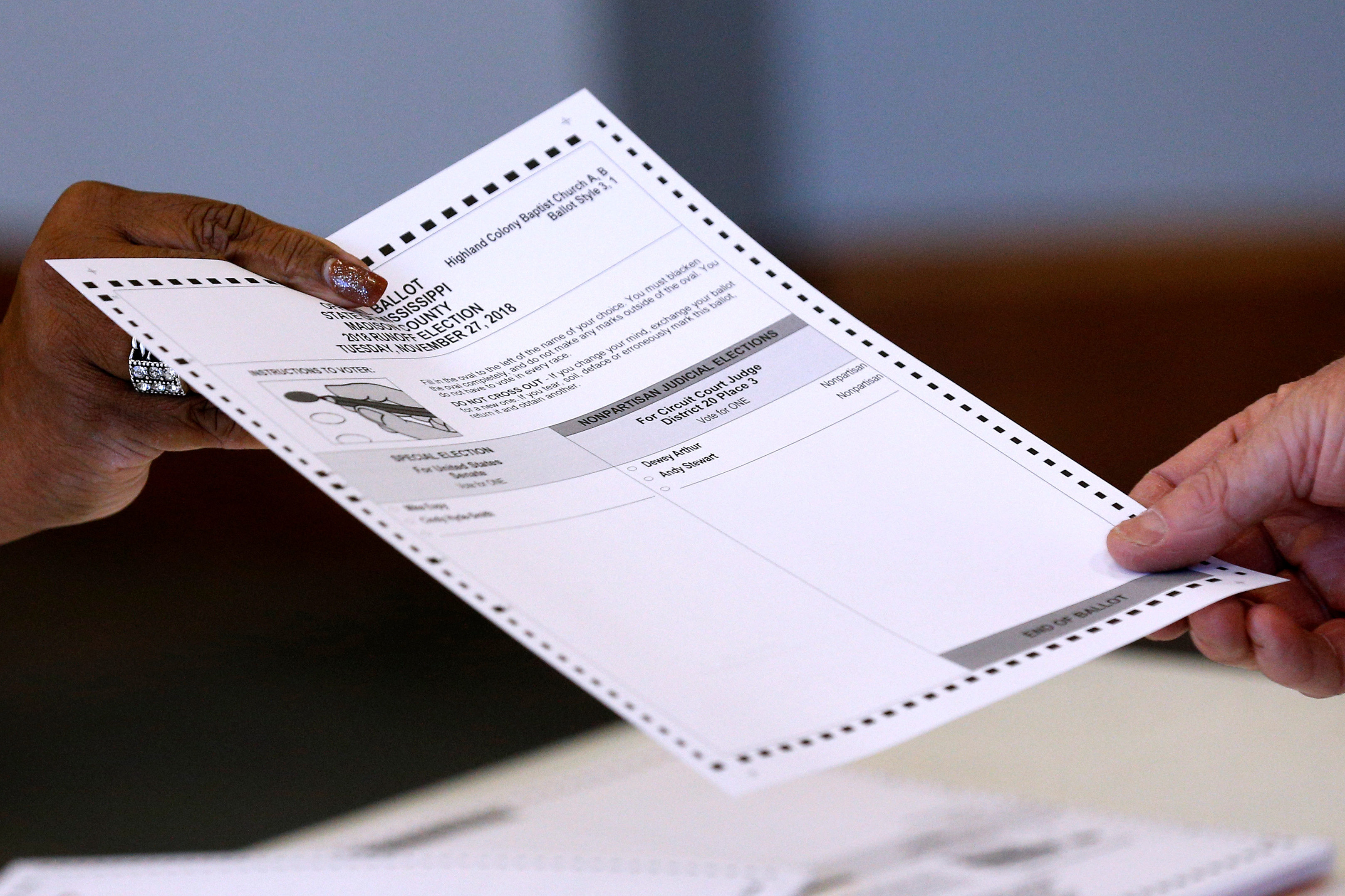 An election official hands a ballot to a voter at a polling station in Ridgeland