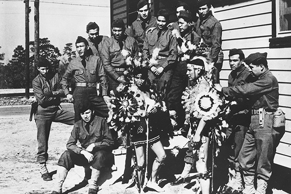 Fourteen Comanche Code Talkers who served in the US military in World War II attending basic training at Fort Benning, Georgia, April, 1941. Charles Chibitty (third from right) was dressed in Comanche dance regalia. National Archives