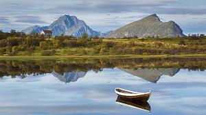 En båt i et vann i et naturlandskap med en hytte i Lofoten.