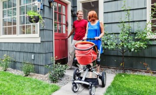 young family on their way out to take a walk with their new baby in a stroller