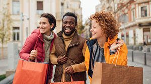 Closeup front view of group of multi ethnic people smiling and holding shopping bags.