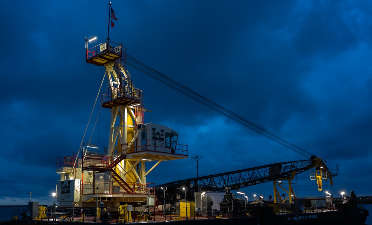 Derrickboat in early morning with lights luminating the crane with blue clouds in the background.