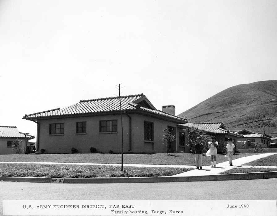 House by a hill with three children in front.