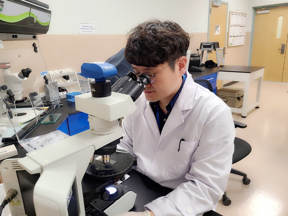 Kim Kyong-ho, U.S. Army Corps of Engineers Far East District Geotechnical Branch chemist, analyzes an asbestos sample collected from an U.S. Army Garrison Yongsan-Casey building through a microscope. According to the U.S. Environmental Protection Agency, asbestos was used in many types of home building products and insulation materials until the 1970s. (U.S. Army photo by U.S. Army Corps of Engineers Far East District)