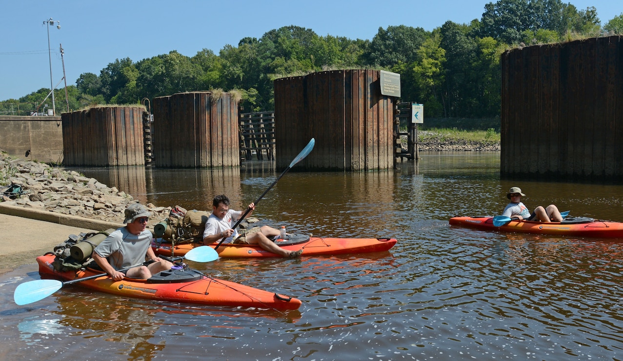 Three paddlers launch their vessels at Lock and Dam 3 on the Cape Fear River.  