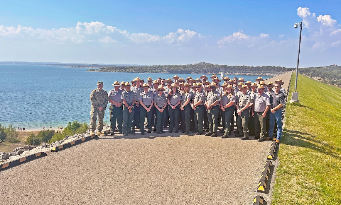 Park rangers pose for a photo on top of a dam