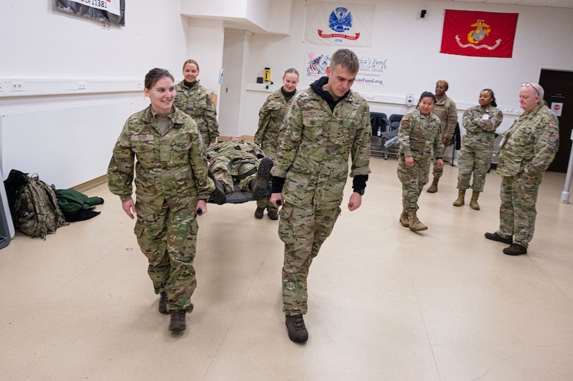 Danish service members carry a person on a stretcher during medical training.