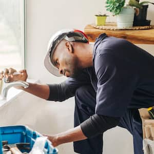 A plumber fixing a leaking bathroom faucet