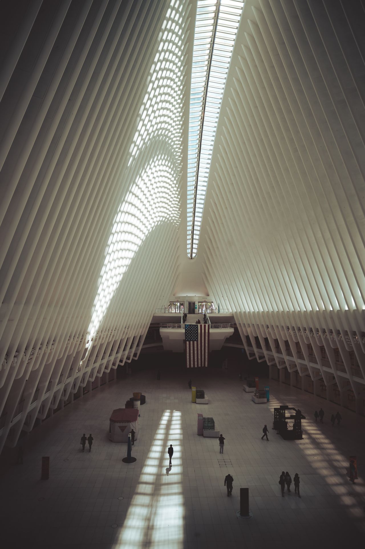 The silhouette of a man walking through sunlit interior of the Oculus building.