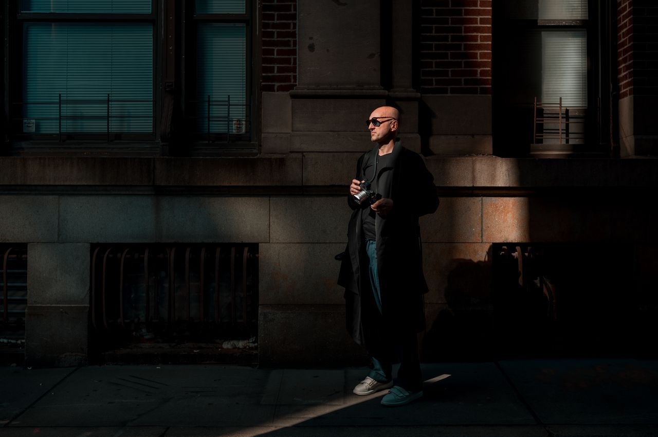 A man holding a camera standing in a beam of light.