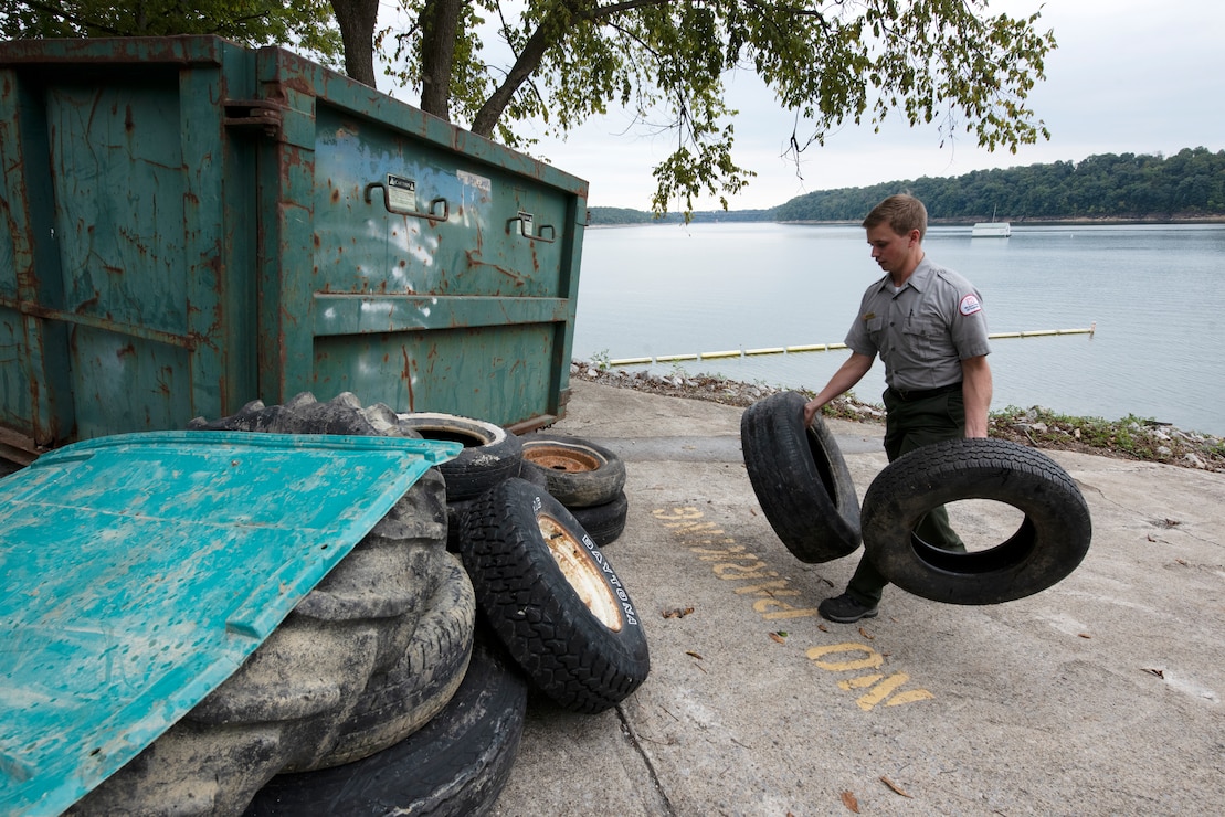 Park Ranger Dylan Norton carries tires collected from the shoreline of Lake Cumberland to a collection point at Waitsboro Recreation Area in Somerset, Kentucky, Sept. 25, 2021. As a member of the U.S. Army Corps of Engineers Nashville District staff at the lake, he helped organize the annual cleanup event and worked with partners and volunteers to pick up tons of trash. (USACE Photo by Lee Roberts