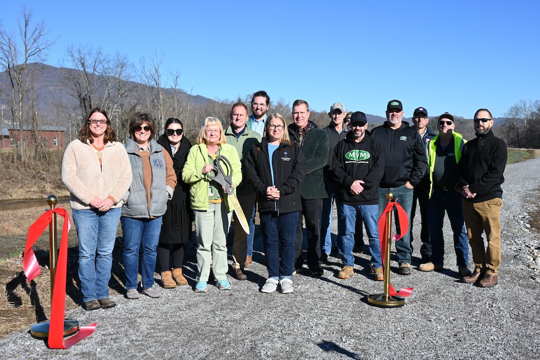 Group of people stand with oversized scissors.