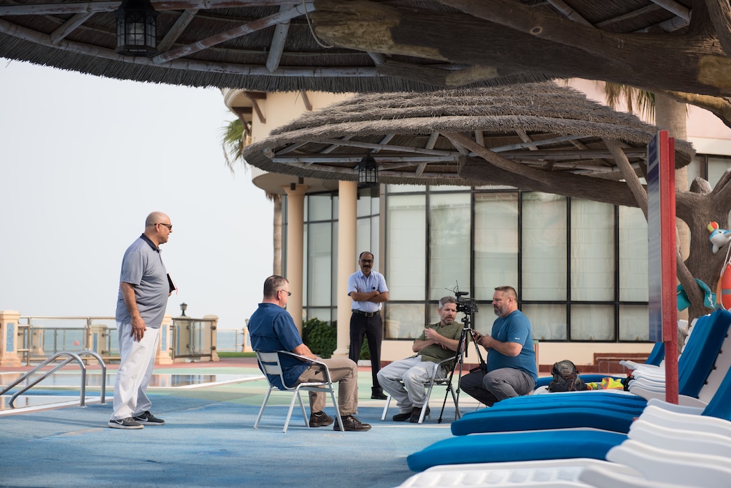 A group of people are on a patio while a video interview is in process.