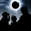 Silhouettes of two children and a woman watching the diamond ring effect on a totally eclipsed Sun.