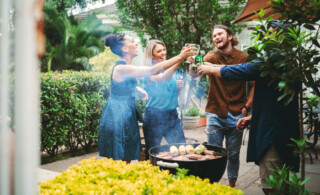 friends grilling out and toasting drinks in the backyard