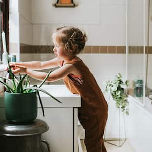 A little girl washing her hands in bathroom sink