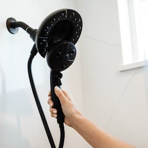 A woman’s hand holding a black shower head