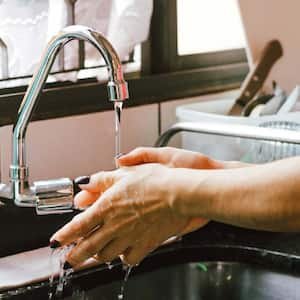 A woman washing her hands in the kitchen sink