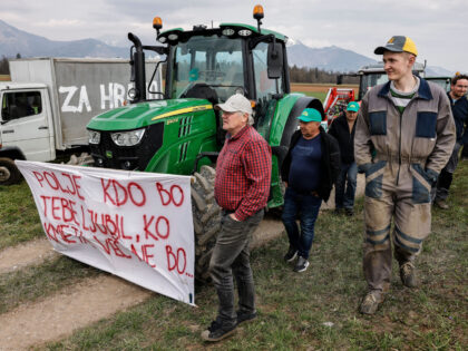 KRANJ, SLOVENIA - 2023/03/24: Farmers walk by a tractor with a sign that says 'Who will lo