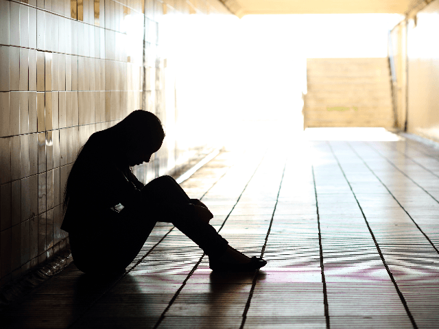 Teenager depressed sitting inside a dirty tunnel - stock photo