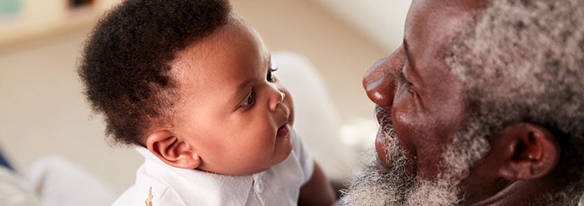 Older, smiling man holding baby