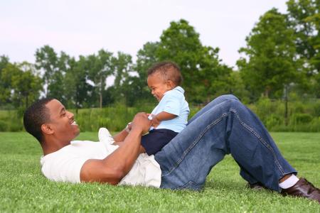 A father and his little son playing on grass.