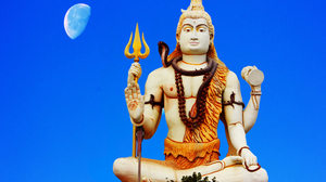 Shiva statue with bright blue sky and Half Moon in the background.