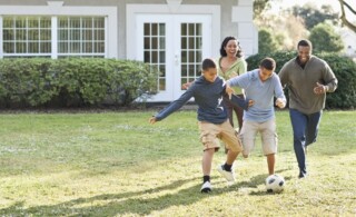 Family playing soccer in backyard