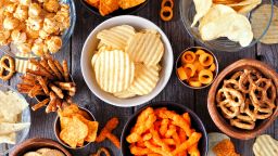 Mixed salty snacks. Flat lay table scene on a rustic wood background.