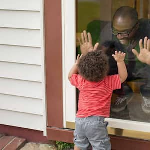 Father and toddler son playing at screen door