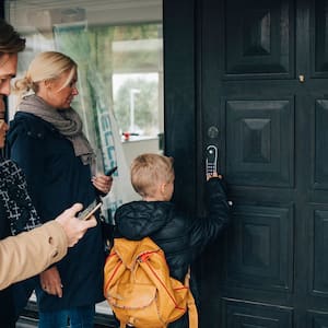 Son unlocks smart lock on door as family looks on