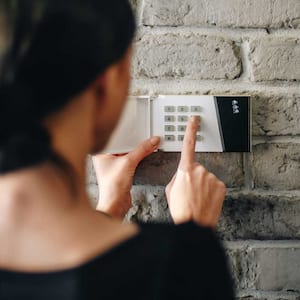 A woman entering a pin on home security system