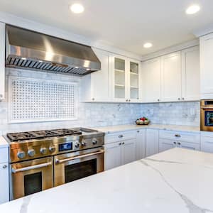 White kitchen with stainless steel appliances and white quartz countertops with gray veins 