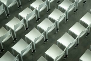 Rows of white plastic chairs on a concrete floor, seen from above