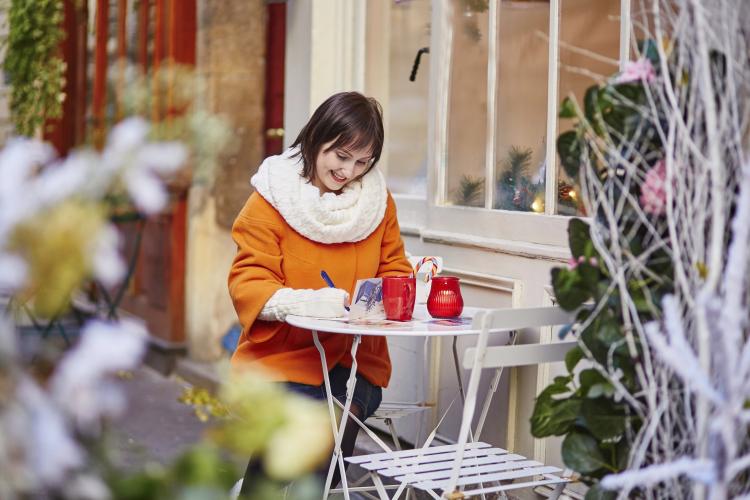 Woman writing Christmas cards in a cafe.