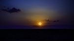 Dark blue sky in the background with a glowing ring around the Sun. The center of the sun is dark.