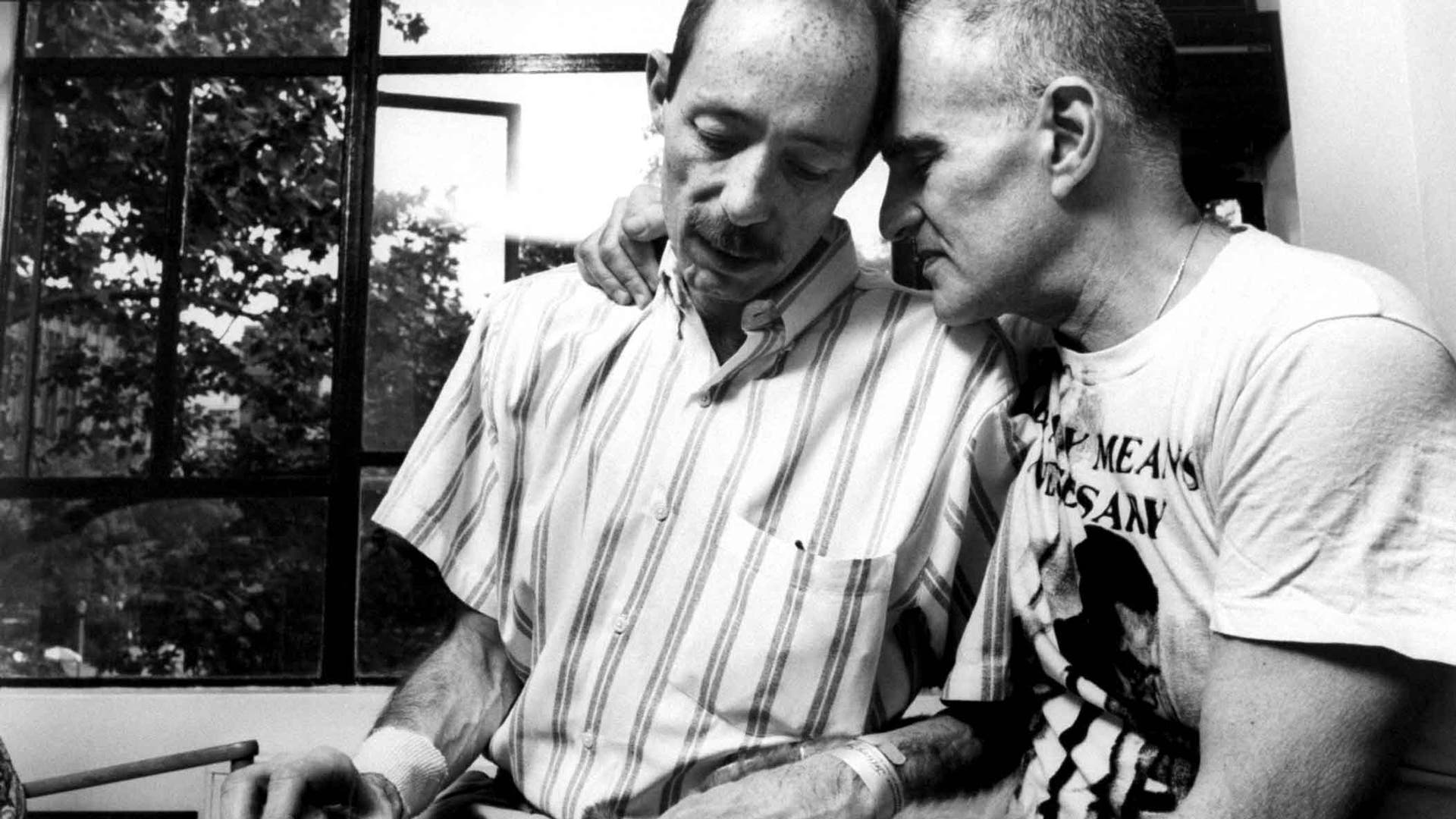 Author/gay activist Larry Kramer, founder of ACT UP, snuggling w. his friend, author & AIDS victim Vito Russo, as he tries to comfort him while petting his dog at home