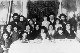 Portrait of the Ehrlich family seated around the family table. Munkacs, Czechoslovakia, 1930.
Among those pictured is Elizabeth Ehrlich (later Roth) standing in the middle of the back row in a light dress, and Rella Ehrlich (front row, second from the right). Elizabeth was born in Munkacs. In 1944 she was confined to the ghetto there before being deported with her family to Auschwitz. She was later transferred to a camp in Bydogszcz, Poland, and from there to the Stutthof concentration camp.