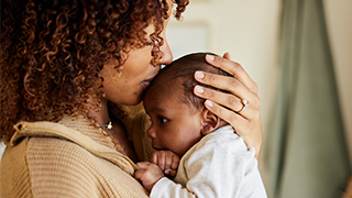 mother kissing newborn baby on head