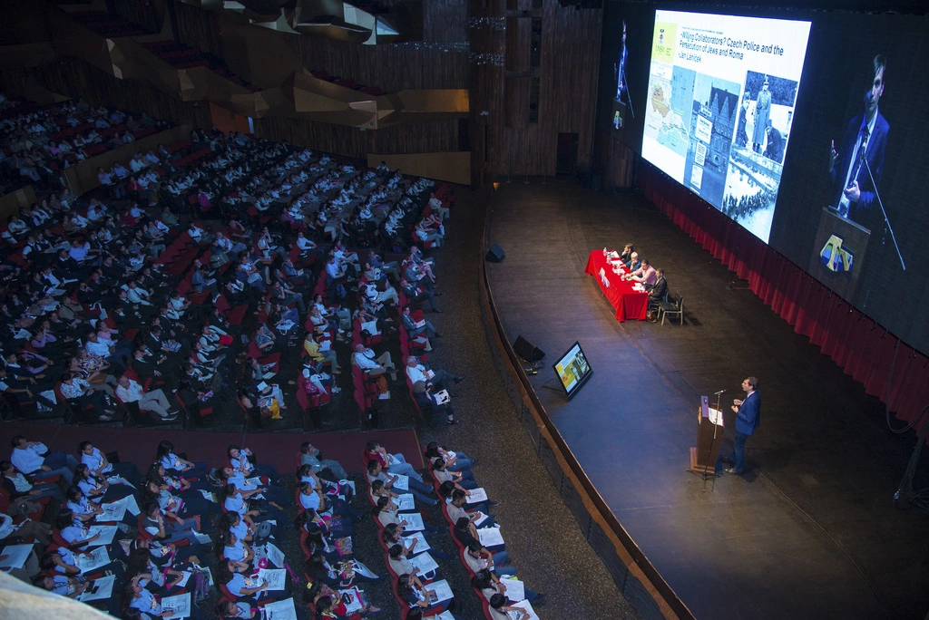 A large audience watching a panel from the Holocaust Memorial Museum discuss on stage