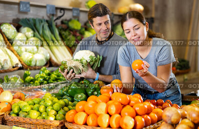 Husband and wife choose fresh fruits and vegetables together in grocery supermarket